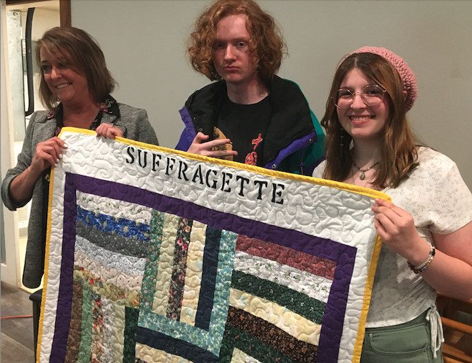 students presenting quilt