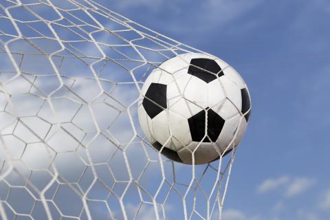 Soccer ball hitting back of net in a soccer goal.