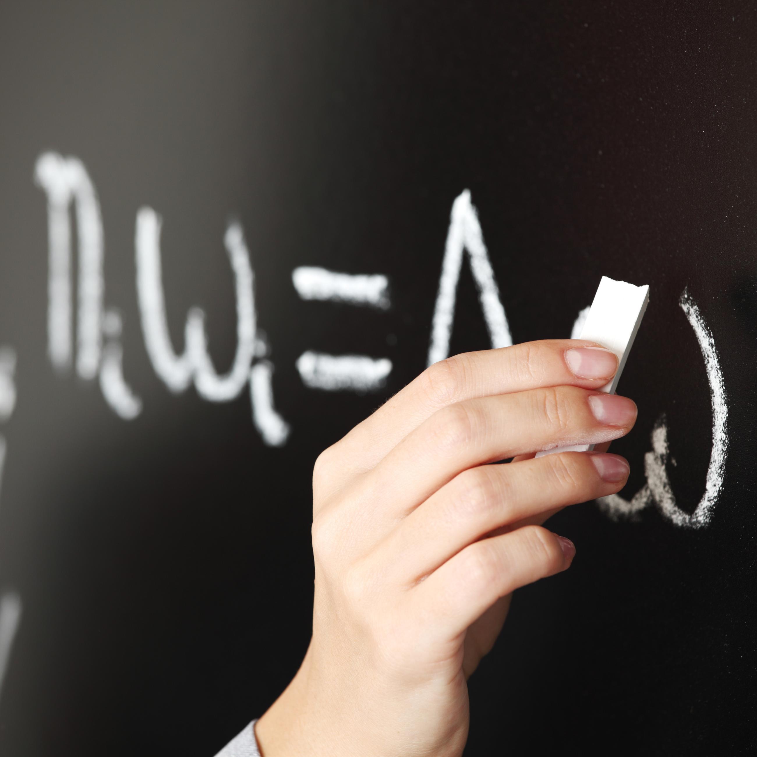 Teacher writing math equation on a chalkboard