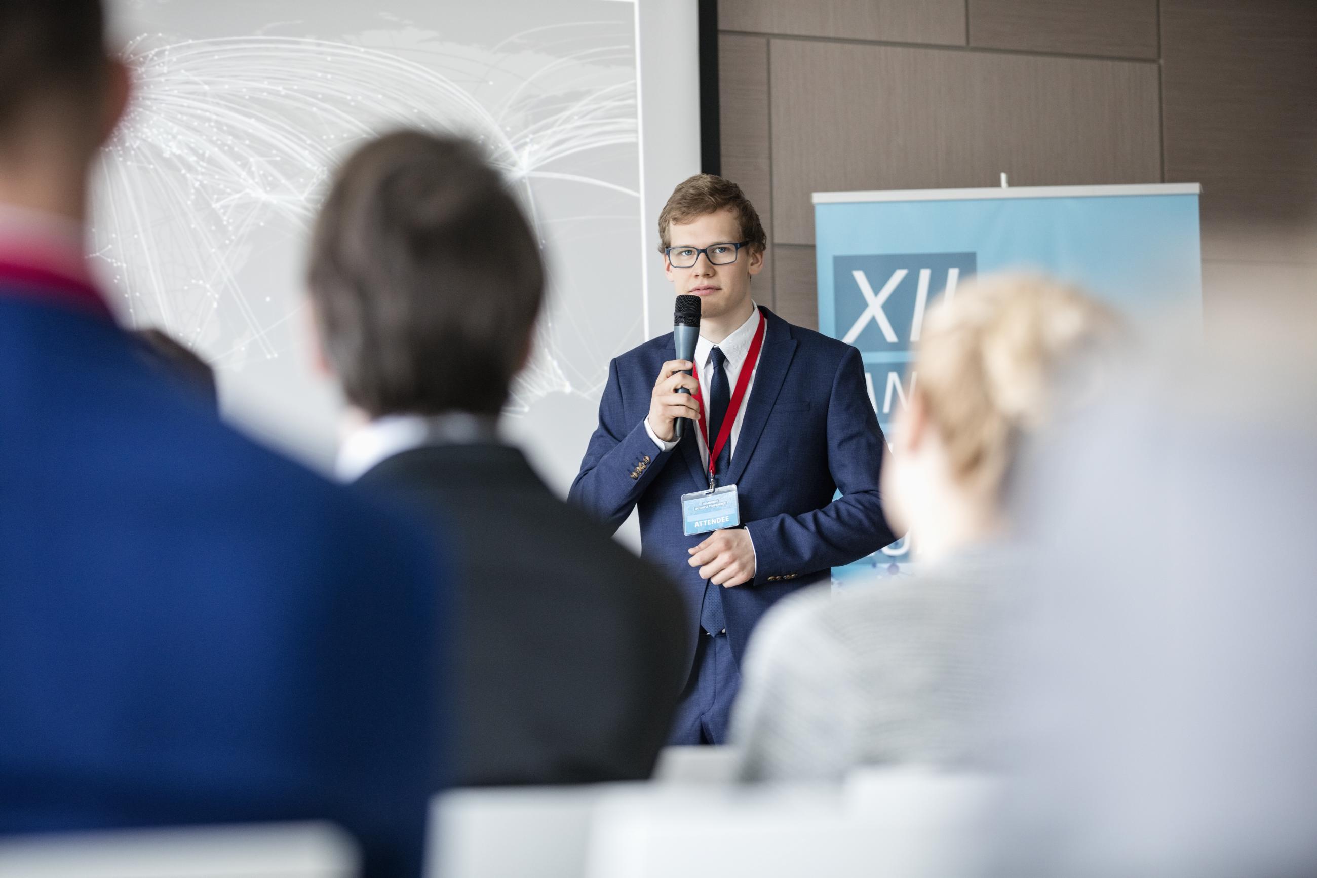 Young man giving public presentation at a conference.