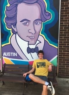 student on bench in front of mural